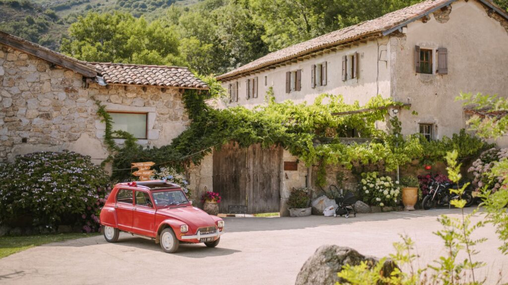Bâtisse du Mas Nouveau et voiture ancienne rouge devant le porche