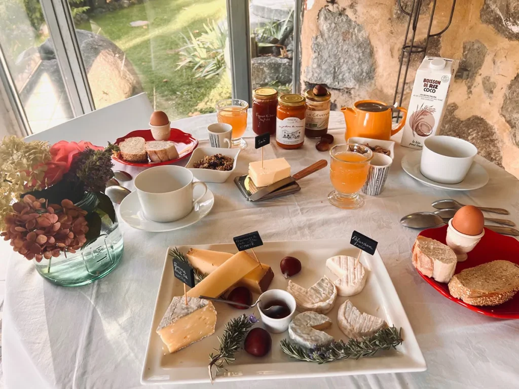 Petit-déjeuner servi avec fromages, confitures et jus de fruits