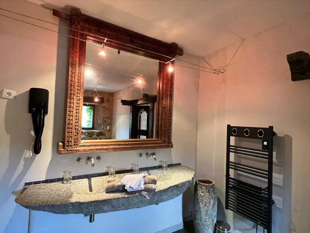 Salle de bain avec vasque en pierre et grand miroir doré